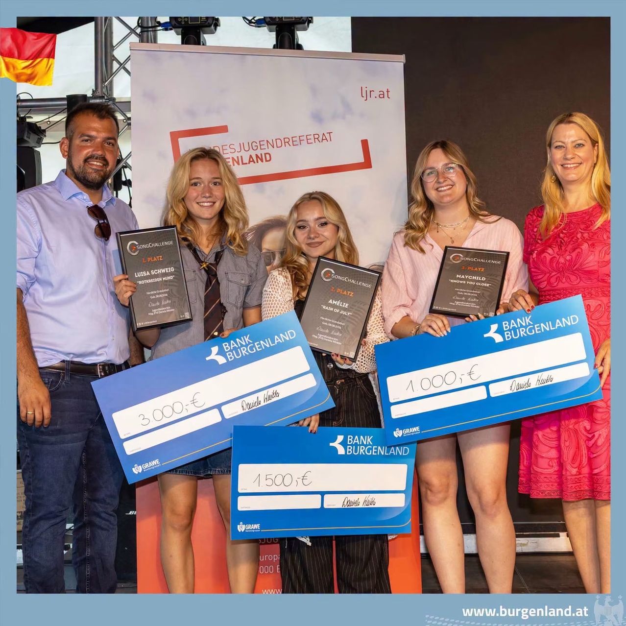 Eine Gruppe von Menschen steht zusammen und hält Urkunden und Schecks. Sie lächeln und posieren für ein Foto. Die Schecks sind von der Burgenland Bank und haben Beträge von 1.000, 1.500 und 3.000 Euro.