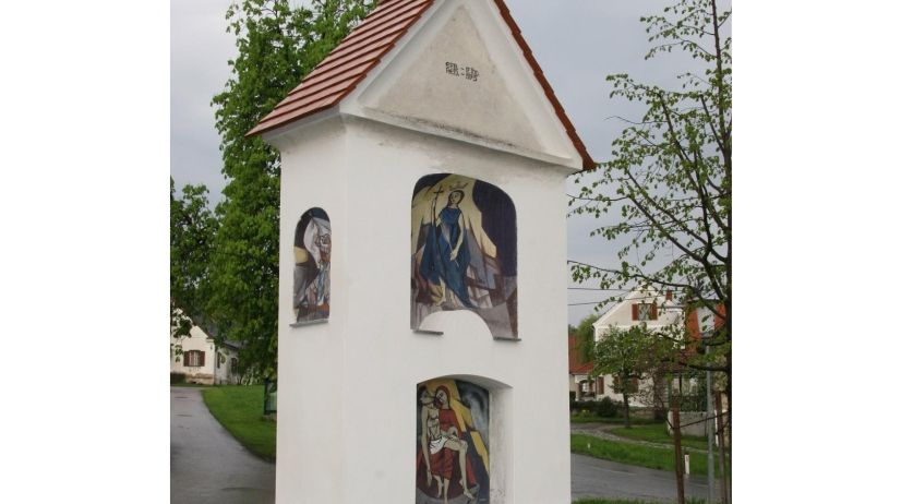 Eine weiße Kapelle mit einem roten Dach und drei Gemälden religiöser Figuren. Die Kapelle befindet sich in einem Grasbereich mit einem Weg. Der Text auf der Oberseite lautet 'Maiandaht'. Das Datum '16. Mai 2026' ist unten geschrieben.