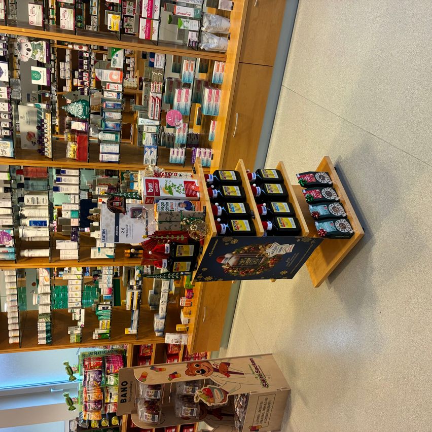 Ein Geschäft mit Regalen voller verschiedener Produkte, darunter Gesundheitsergänzungsmittel und Süßigkeiten, auf einem gefliesten Boden ausgestellt.