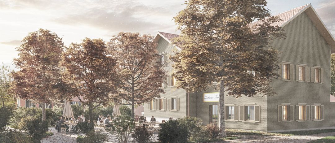 Ein Outdoor-Café-Bereich mit Menschen, die an Tischen sitzen. Die Umgebung zeigt ein modernes Gebäude mit Backsteinwänden, einem roten Dach und einem Schild mit der Aufschrift 'Gasthof Frei'. Bäume mit Herbstlaub und Sonnenschirme ergänzen die Szene.