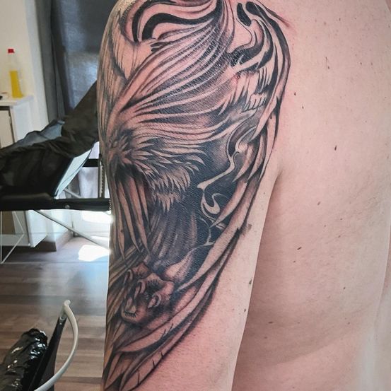 Ein schwarz-graues Tattoo eines heulenden Wolfes am Arm einer Person, möglicherweise in einem Tattoo-Studio.