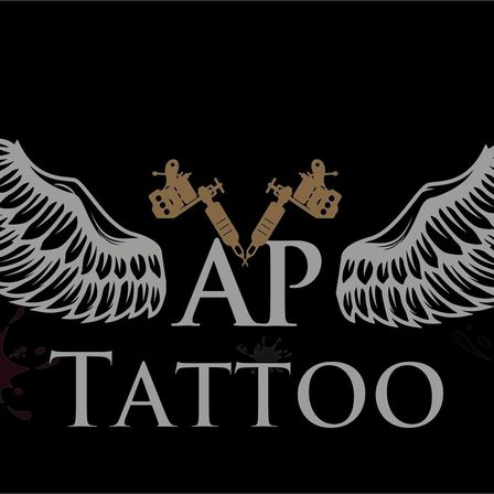 AP Tattoo Logo mit zwei goldenen Flügeln auf schwarzem Hintergrund, zwei goldene Tattoo-Pistolen mit Flügeln in der Mitte und dem Wort 'Tattoo' darunter.