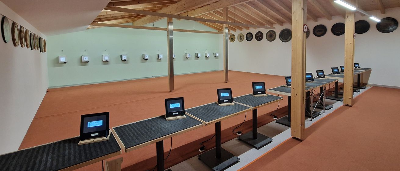 Ein leerer Schießstand mit mehreren elektronischen Zielen an der Wand und mehreren Schießständen mit Monitoren davor.
