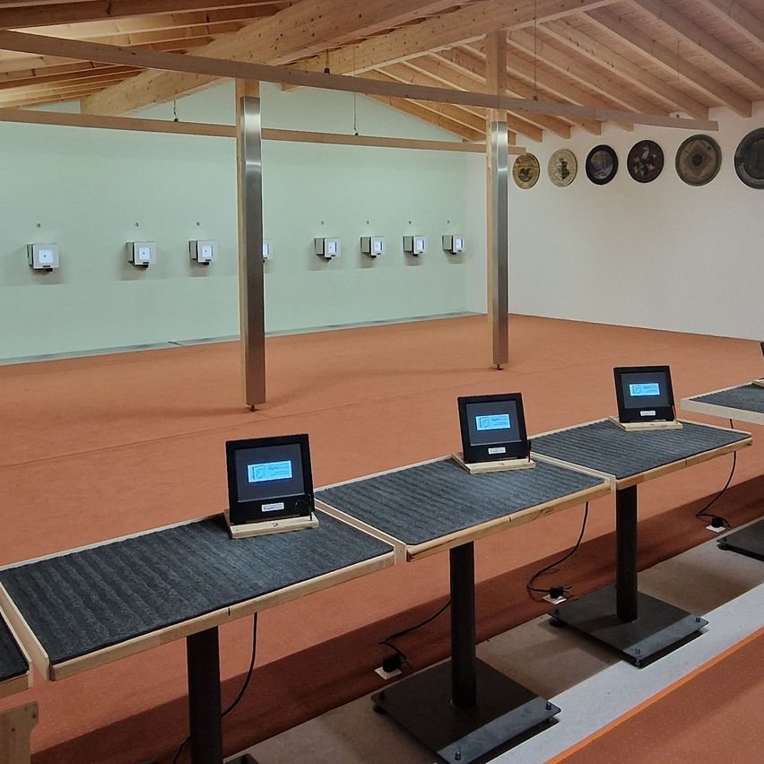 Ein leerer Schießstand mit mehreren elektronischen Zielen an der Wand und mehreren Schießständen mit Monitoren davor.