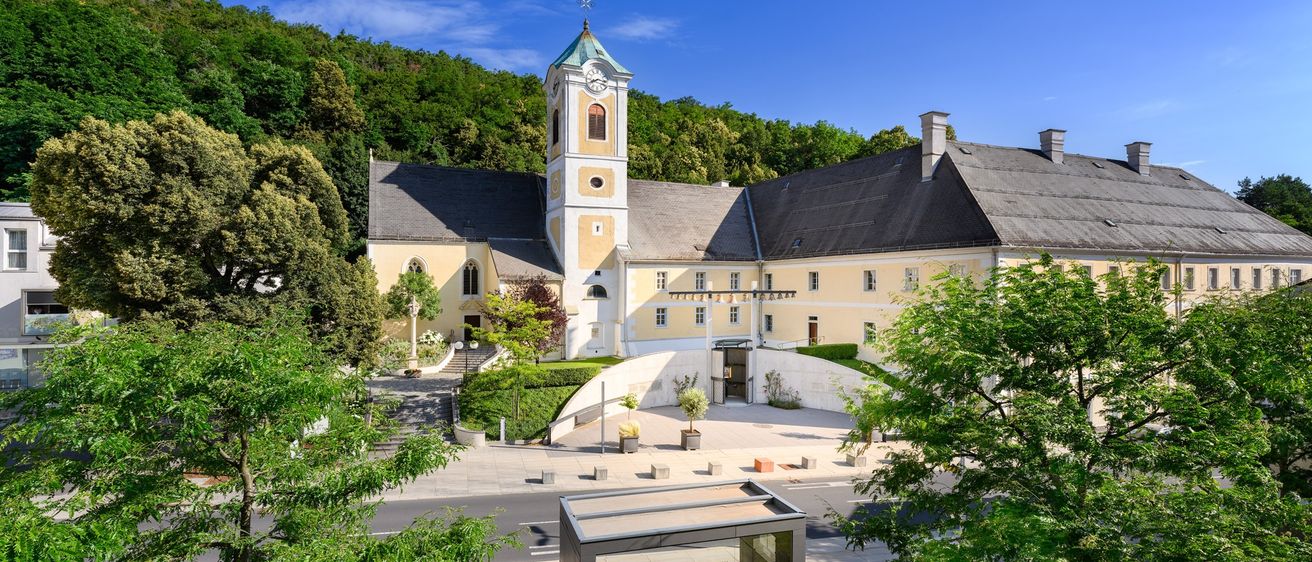 Luftaufnahme der St. Georg Kirche mit Glockenturm, Glasüberdachung und umgebender Grünfläche.