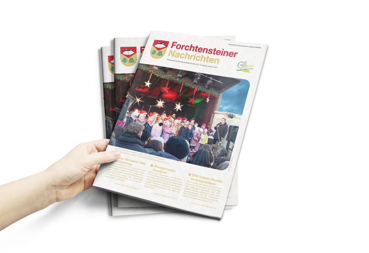 Eine Person hält einen Stapel 'Forchtensteiner Nachrichten' Zeitschriften. Das Cover zeigt ein Foto von Kindern, die in einer festlichen Umgebung mit Sternen und Lichtern singen. Der Text ist in Deutsch.