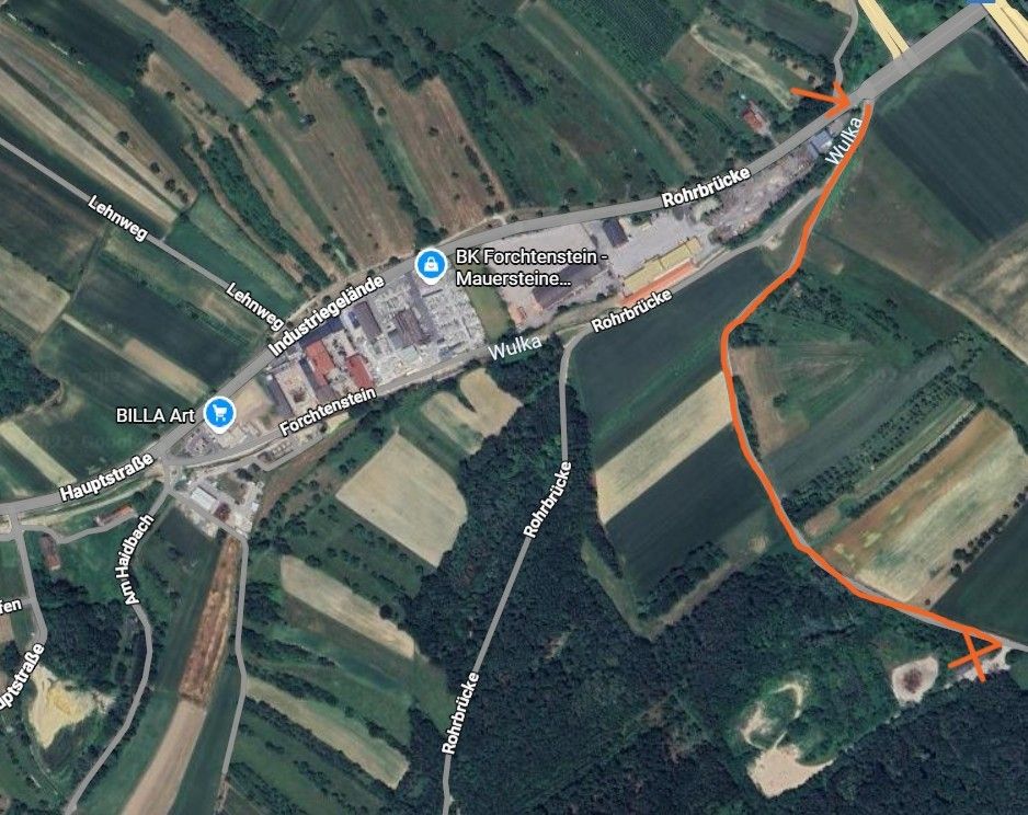 Eine Karte mit einer Luftaufnahme eines Industriegebiets mit verschiedenen Straßen und Brücken. Das Gebiet hat Felder und Wälder. Ein Pfad ist orange hervorgehoben.