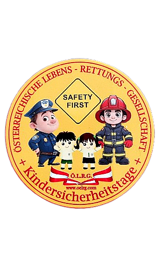 Ein gelber runder Abzeichen zeigt eine Sicherheitsbotschaft mit Zeichentrickfiguren eines Polizisten, eines Feuerwehrmanns und zweier Kinder. Der Text lautet 'Sicherheit zuerst' und 'Österreichische Lebens-Rettungs-Gesellschaft + Kindersicherheitstag' mit einer Website-Adresse.