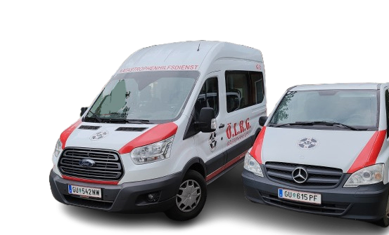 Zwei Fahrzeuge, die vor schwarzem Hintergrund geparkt sind. Ein weißer Ford-Transporter mit rotem Zierstreifen und der Aufschrift 'O.L.R.G.' an der Seite. Ein weißer Mercedes-Transporter mit rotem Zierstreifen und dem Kennzeichen 'GU 615 PF.'