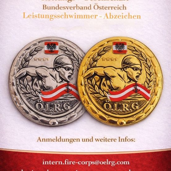 Zwei Medaillen, eine silberne und eine goldene, sind ausgestellt. Beide haben ein Bild eines Schwimmers und den Text O.L.R.G. Über den Medaillen steht der Titel 'Leistungsschwimmer - Abzeichen'. Die Medaillen sind von Lorbeerblättern umgeben.