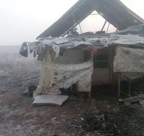 Ein beschädigtes Schutzhaus mit einem zerrissenen Dach und freiliegenden Wänden, umgeben von einer kargen Landschaft.