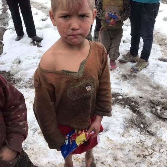 Ein junger Junge steht im Schnee und hält eine Tüte Snacks, während andere hinter ihm stehen.