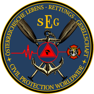Ein rundes Emblem mit einem roten Dreieck und einer Herzschlaglinie in der Mitte, mit zwei gekreuzten Rudern und einem Anker. Darunter steht der Text 'SEG CIVIL PROTECTION WORLDWIDE'.