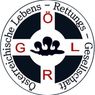 A circular emblem with a cross design, featuring the letters 'G', 'R', and 'L' in red, white, and black. The emblem has a watermark in the center and the text 'Lebensschutz' written in German around the edge.