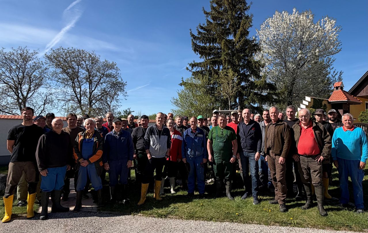 Eine Gruppe von Menschen in Arbeitskleidung und Stiefeln posiert für ein Foto vor Bäumen und Gras.