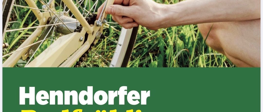 Eine Person repariert ein Fahrradrad mit einem Werkzeug auf einem Rasen. Der Poster sagt 'Henndorfer Radfruhling' und 'Bring dein Rad zum kostenlosen Fahrradcheck!' in Grün.