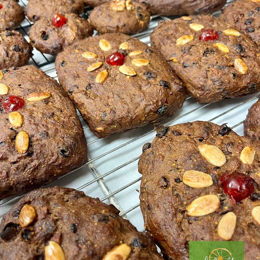 Eine Nahaufnahme von mehreren Schokoladenkeksen mit Mandeln und Kirschen auf einem Kühlrost.