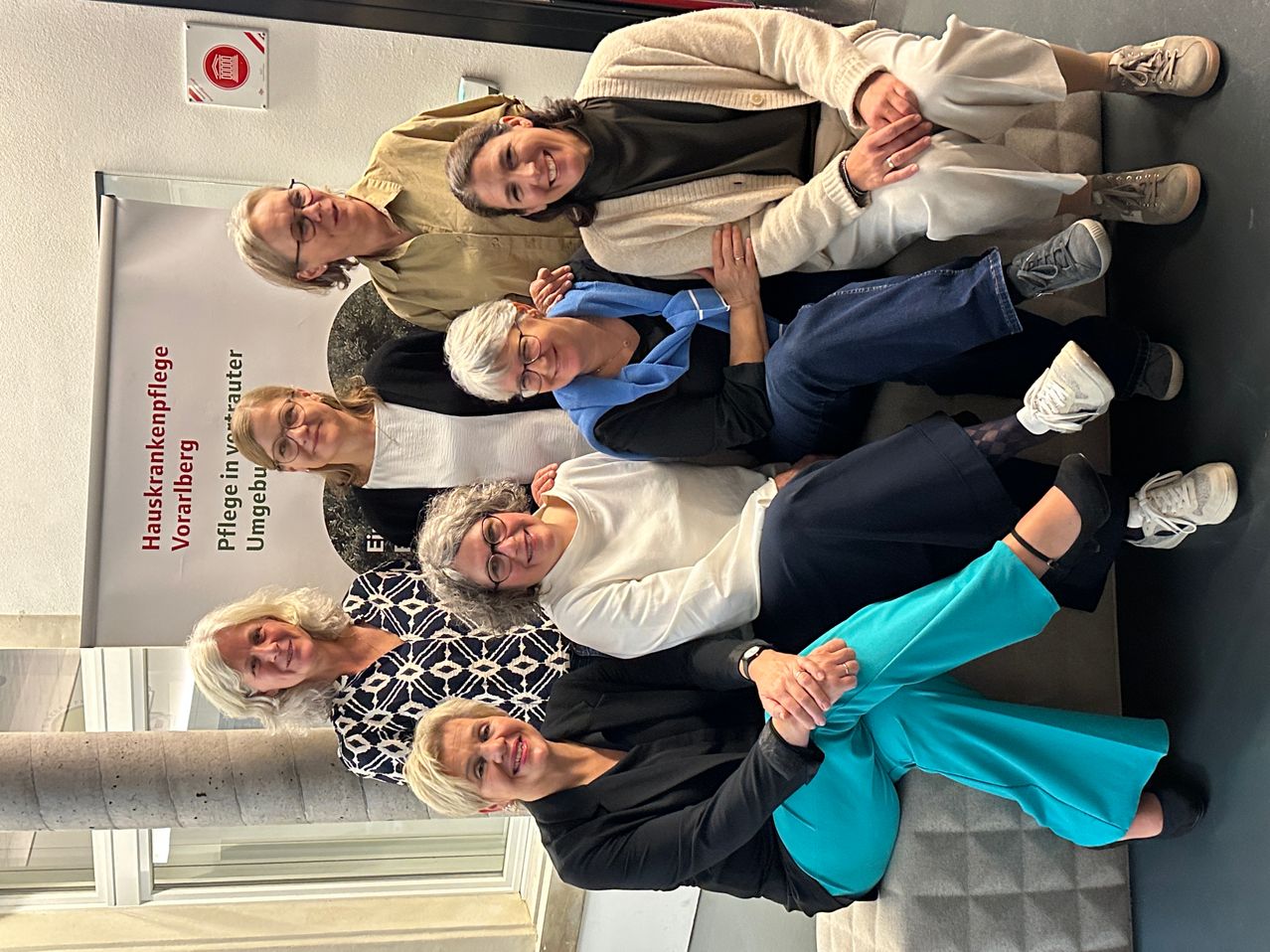 Eine Gruppe von Frauen mit unterschiedlichen Frisuren und Kleidungsstilen posiert für ein Foto vor einem weißen Banner.