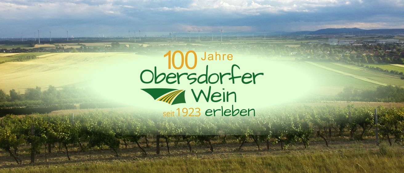 Eine Weinbergslandschaft mit einem grünen Überlagerung, die '100 Jahre Obersorfer Wein seit 1923 erleben' anzeigt. Im Hintergrund sind Windturbinen und ein bewölkter Himmel zu sehen.