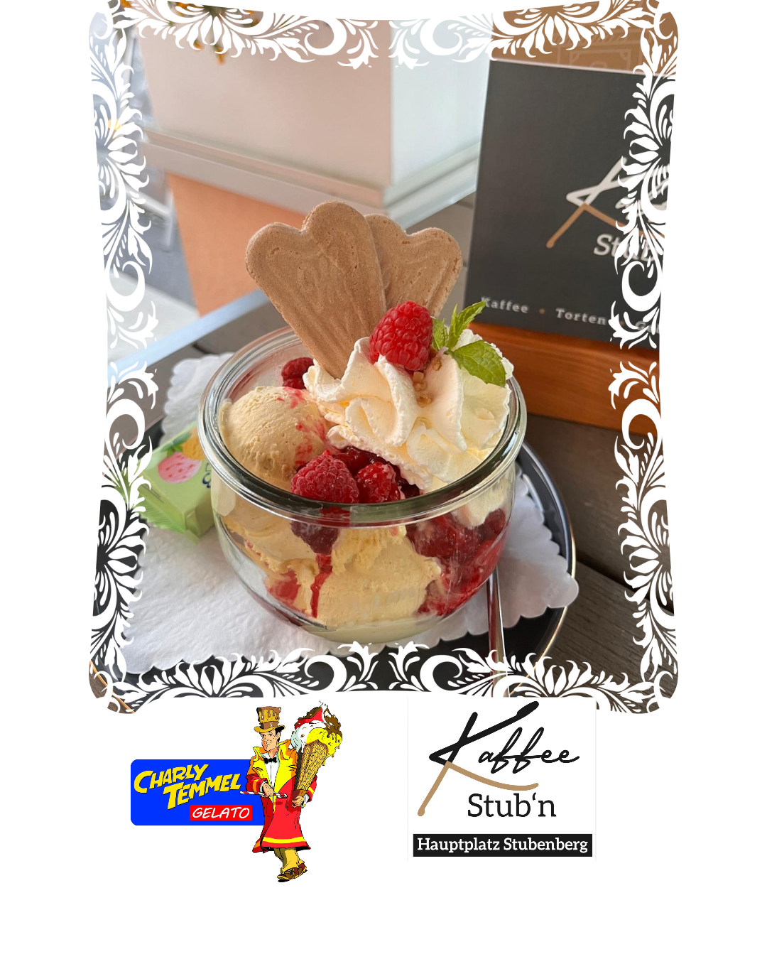Ein Glasbecher gefüllt mit Eiscreme, Himbeeren, Schlagsahne und einem herzförmigen Waffelkek. Ein hölzernes Schild zeigt rechts Kaffee Stuben.