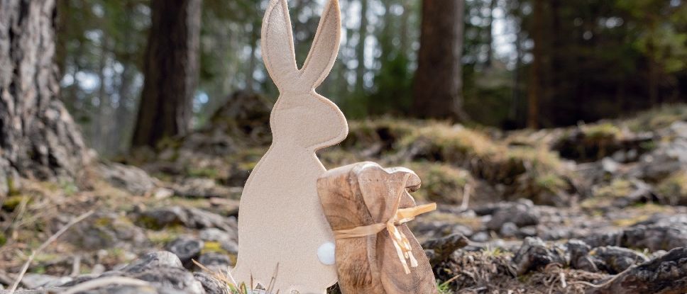 Eine Pappfigur eines Kaninchens und ein kleiner brauner Beutel, der mit einem Band befestigt ist, liegen auf einer rauen, felsigen Oberfläche.