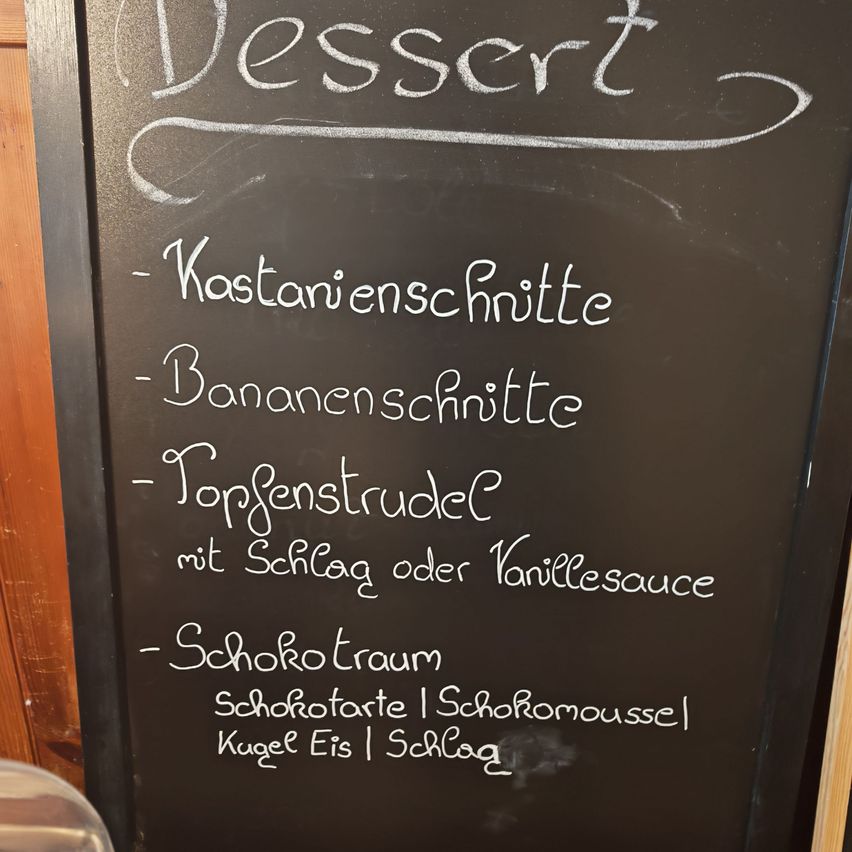 Ein Kreidetafel-Menü mit dem Wort Dessert oben. Darunter sind Kastanienschnitte, Bananenschnitte, Topfengulasch mit Schlag oder Vanillesauce, Schokoladentraum, Schokoladentarte, Schokoladenmousse, Eis und Schlag aufgeführt.