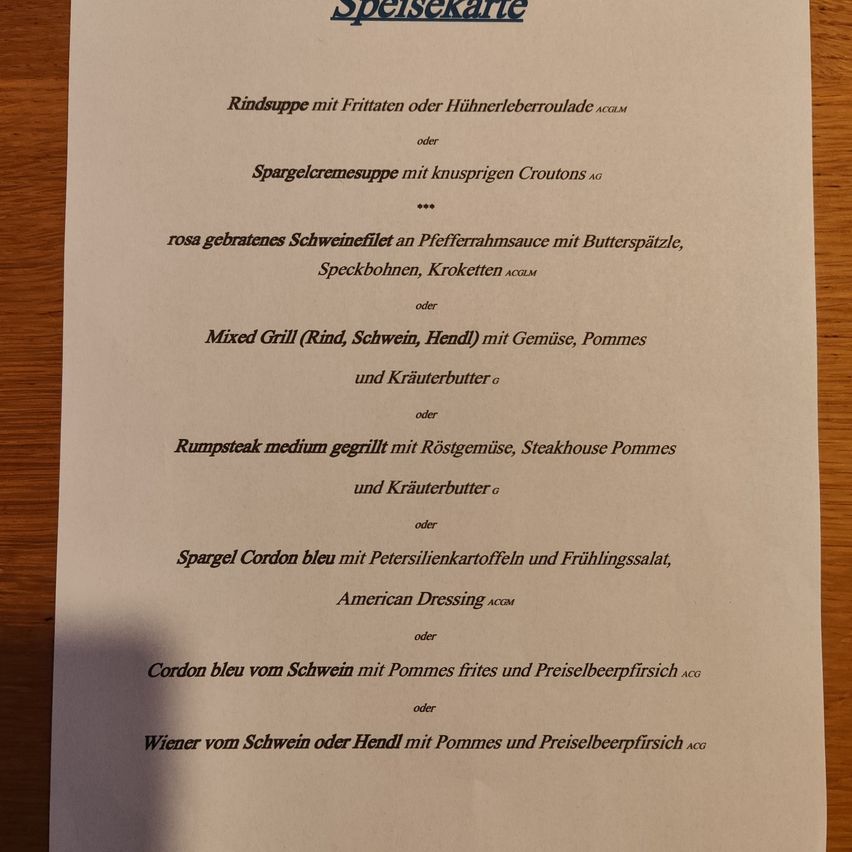 Eine Speisekarte listet Rindsuppe mit Fritten oder Hühnerleberroulade, Spargelcremesuppe mit knusprigen Croutons, rosa gebratenes Schweinefilet an Pfefferrahmsauce und weitere Gerichte auf.
