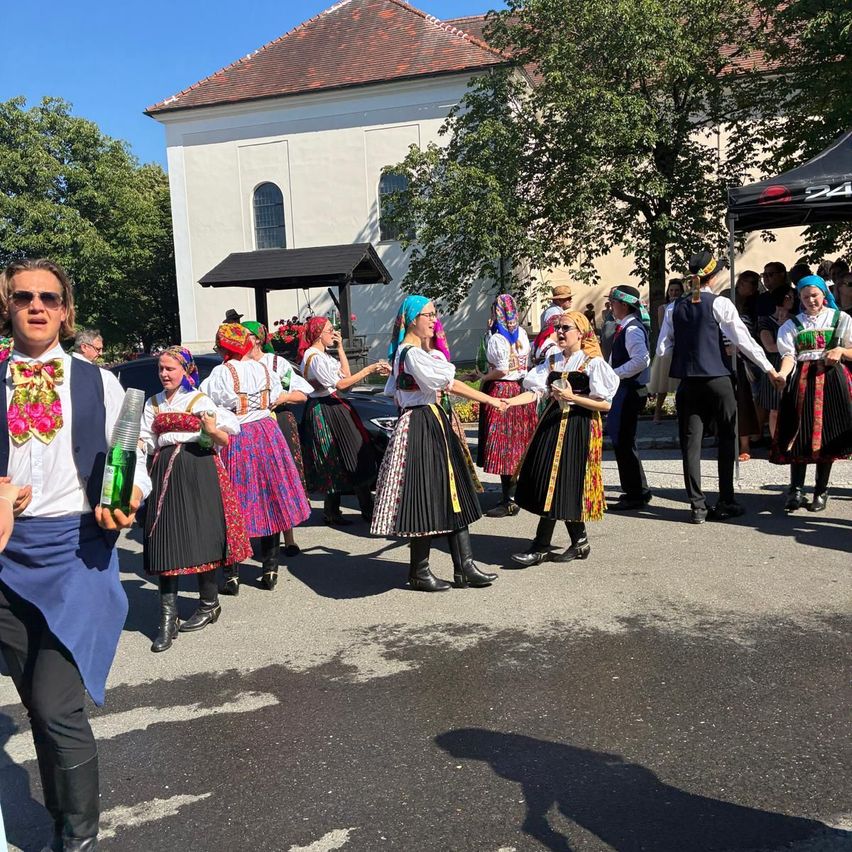 A group of people dressed in traditional costumes are dancing in front of a church.