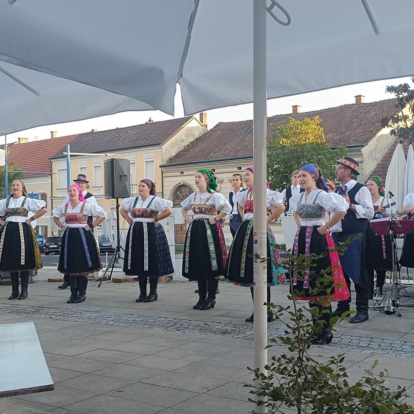 A group of women in traditional costumes performing on a city street.