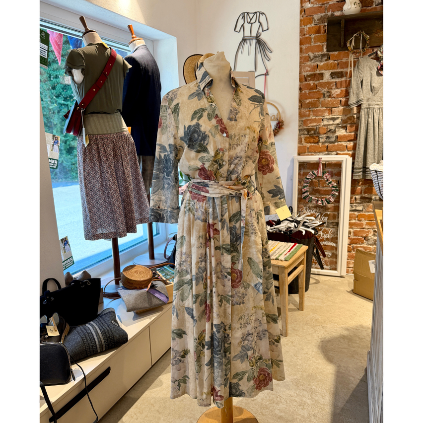 A floral dress on a mannequin in a clothing store with a brick wall in the background.