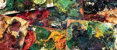 Mehrere Paletten gefüllt mit verschiedenen Farben. Jede Palette enthält dicke Schichten verschiedener Farben. Die Farbe befindet sich in verschiedenen Trocknungsphasen.