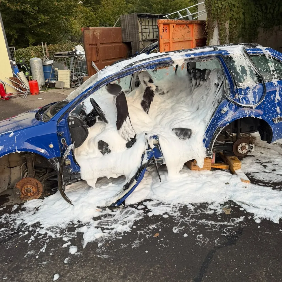 Ein blaues Auto ist zerbrochen und mit Schaum gefüllt, es steht mit offener Tür auf der Straße.