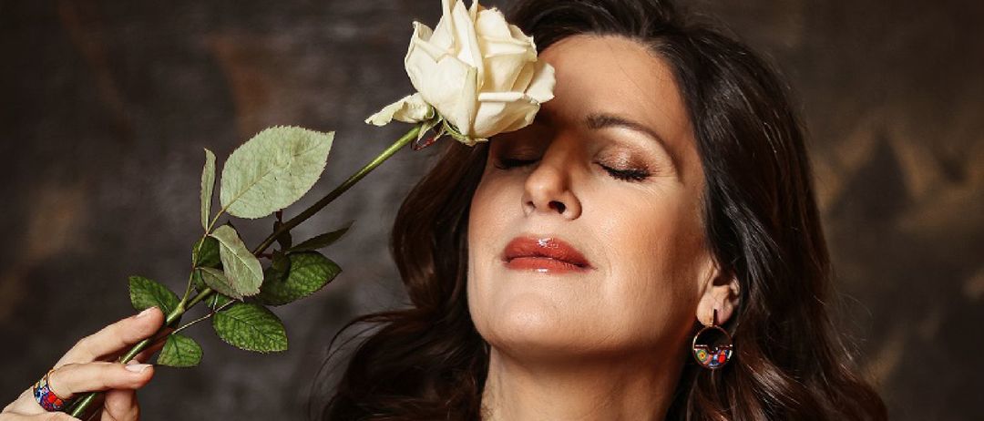 Eine Frau hält eine weiße Rose in der Nähe ihres Gesichts. Der Text lautet 'ven! Geschichten. 17 Songs.' Sie trägt ein schwarzes Hemd und eine Halskette. 'St. Gertrud' und 'INE ZMAJLOVA' sind über ihr geschrieben. 'AJLOV - Violine C - Klavier' steht darunter.