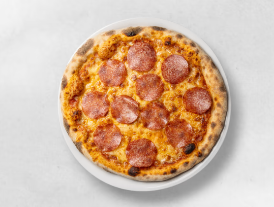 Eine frisch gebackene Pepperoni-Pizza auf einem weißen Teller vor weißem Hintergrund.