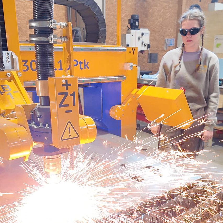 Bild enthält, Accessories, Sunglasses, Person, Worker, Metalworking, Face, Building, Factory, Bulldozer, Machine