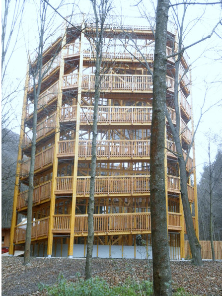 Ein mehrstöckiges Holzgebäude mit Balkonen und Treppen in einem Wald.