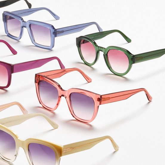 Eine Sammlung von sechs Sonnenbrillenpaaren in verschiedenen Farben, einschließlich Blau, Grün, Pink und Pfirsich, auf weißem Hintergrund präsentiert.