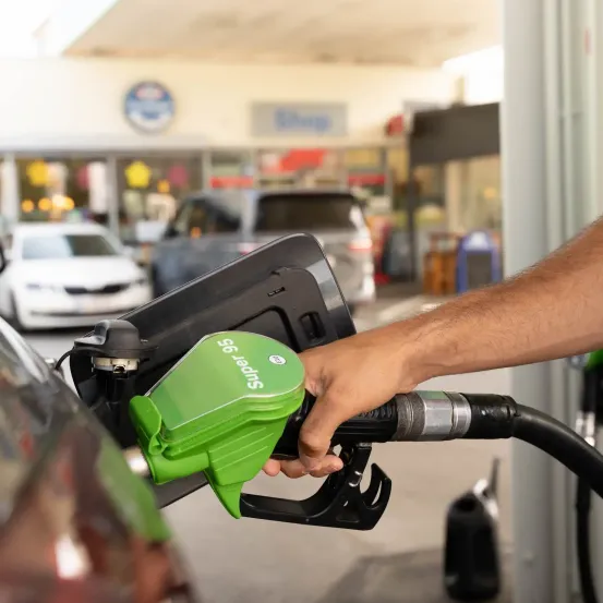 Eine Person füllt ihr Auto mit grünem Kraftstoff an einer Tankstelle auf.