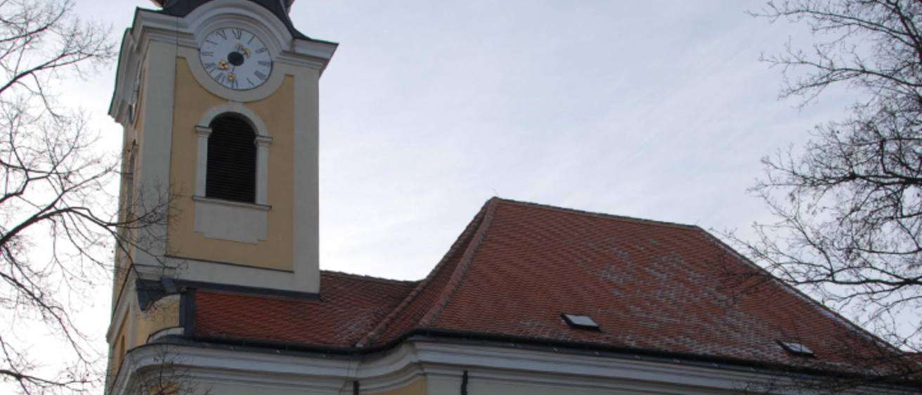 Ein hohes Gebäude mit einem Glockenturm, einem Fenster und einem braunen Dach. Die Uhr zeigt 10:10. Das Gebäude hat ein kleines Fenster auf dem Dach.