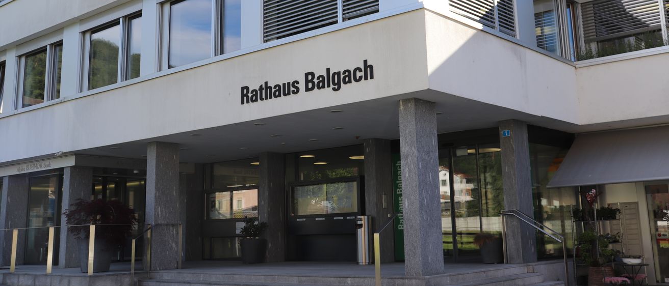 Die Vorderseite des Rathaus Balgach-Gebäudes hat ein modernes Design mit Glasfenstern und einem großen Schild über dem Eingang.