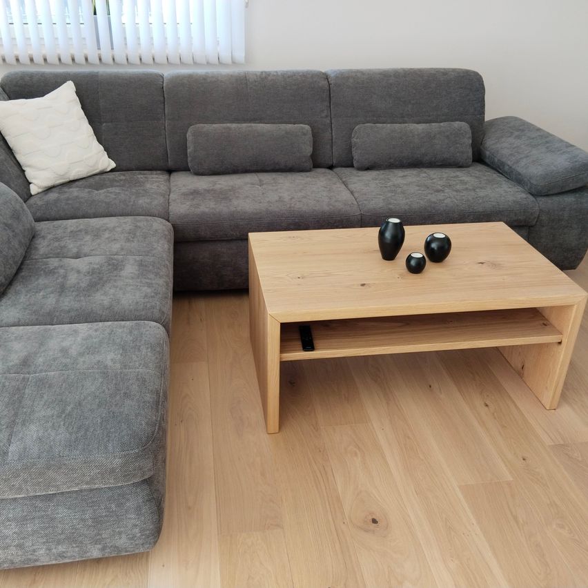 A living room with a gray sofa and two black vases on a wooden coffee table.