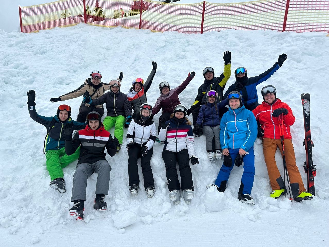 Eine Gruppe von Menschen in Winterkleidung und Helmen posiert für ein Foto im Schnee.