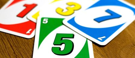 Nahaufnahme von fünf nummerierten Karten eines Spiels, darunter eine grüne Karte mit der Nummer fünf.