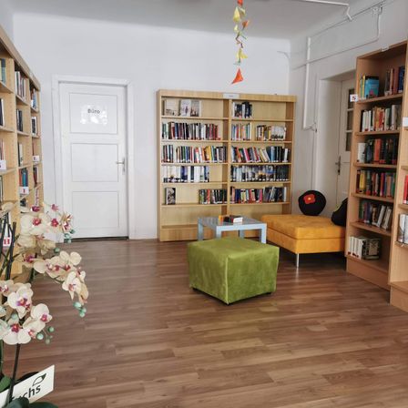 Bild enthält, Furniture, Bookcase, Architecture, Building, Person