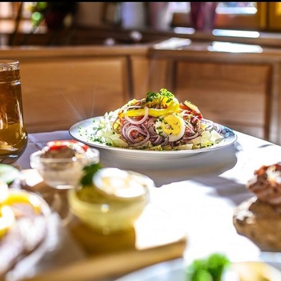 Ein Tisch mit einem Salat, Brot und einem Glas Bier, alles unter hellem Licht.
