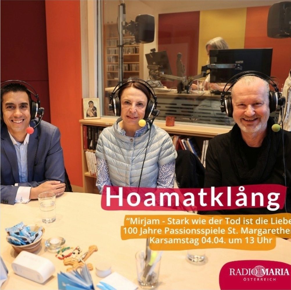 Drei Menschen mit Kopfhörern sitzen in einem Studio vor einem Schreibtisch. Sie lächeln. Ein Glas Wasser und ein Buch stehen auf dem Tisch. Der Text 'Hoamatklang' ist prominent angezeigt.