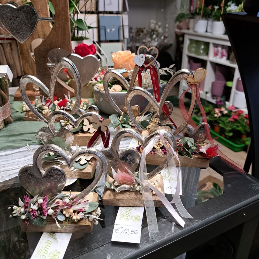 A table with heart-shaped decorations and flowers on it. Each heart is adorned with ribbons and small flowers. The price tag reads EUR 12.50.