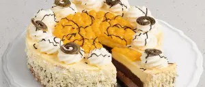 Eine Scheibe Kuchen mit Schokoladen- und Mangoschichten liegt auf einem weißen Teller. Es ist mit Schlagsahne und Wirbeln garniert.