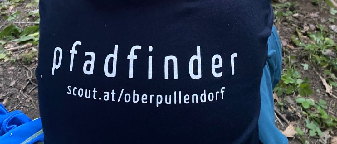 Ein junger Junge in einer Pfadfinder-Uniform sitzt im Wald und beobachtet andere.
