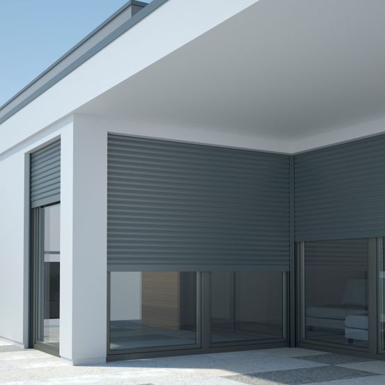 Modernes Hausaußen mit grauen Rollladen-Jalousien und Glastüren, die den klaren blauen Himmel widerspiegeln.